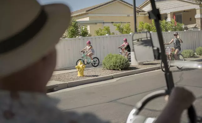 Residents greet Joe Johnston, founder of Agritopia, a community nestled around a plot of agricultural land, as he makes his rounds in his golf cart April 22, 2025, in Gilbert, Ariz. (AP Photo/Annika Hammerschlag)