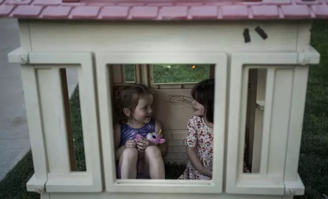 Josie, 3, and Fae Padron, 4, play house in a "kid pod," a cluster of families with more than 20 kids between them, at Agritopia, a community nestled around a plot of agricultural land, April 21, 2025, in Gilbert, Ariz. (AP Photo/Annika Hammerschlag)