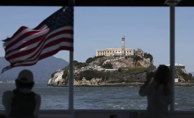People take photos of Alcatraz Island from a ferry in San Francisco, Monday, May 5, 2025. (AP Photo/Jed Jacobsohn)