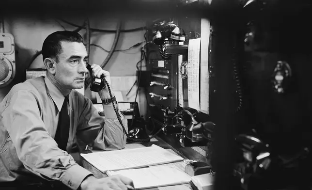 FILE - Senior officer Melvin Kidney works within a 2-inch laminated bullet proof glass at the control center of the Alcatraz Federal Penitentiary in San Francisco Bay, California, March 14, 1956. He supervises all communications and has custody of arms, ammunition, tear gas, etc. (AP Photo/Ernest K. Bennett, File)