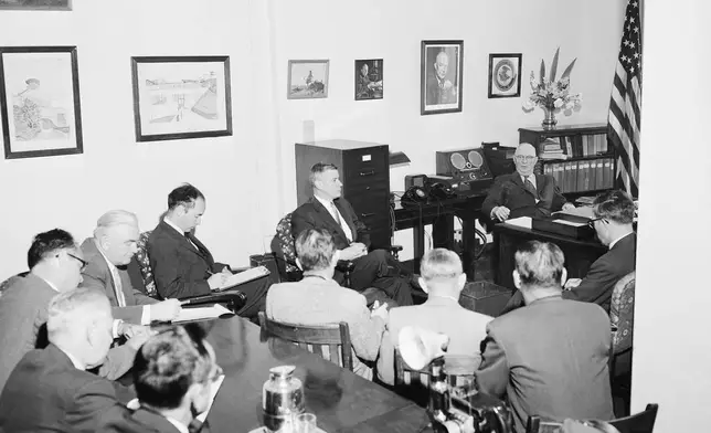 FILE - Warden P.J. Madigan, top right, gives a press conference inside his office at the Alcatraz Federal Penitentiary in San Francisco Bay, California, March 13, 1956. G. Frederick Mullen, director of information, U. S. Dept. of Justice, sits at top center. (AP Photo/Ernest K. Bennett, File)
