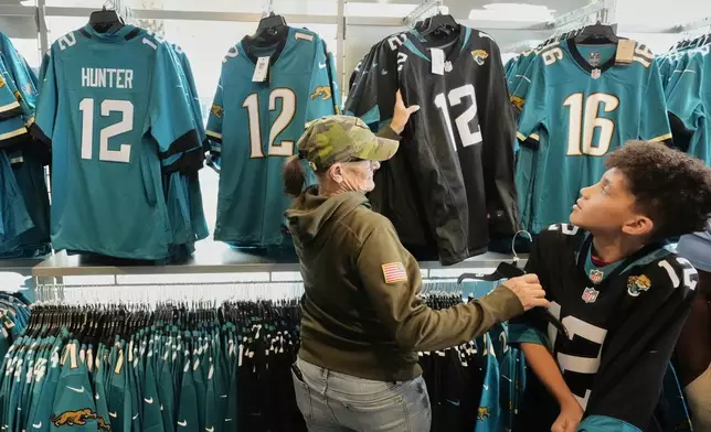 Fans try on Jacksonville Jaguars' Travis Hunter No. 12 jersey at a team store during the NFL football team's rookie minicamp, Saturday, May 10, 2025, in Jacksonville, Fla. (AP Photo/John Raoux)