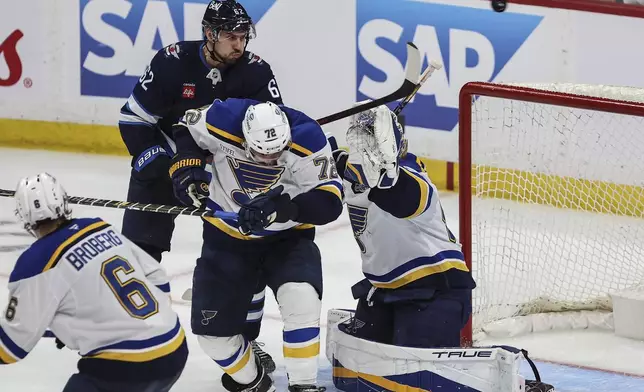 Winnipeg Jets' Nino Niederreiter (62) attempts to tip the puck past St. Louis Blues goaltender Jordan Binnington (50) as Justin Faulk (72) defends during second period NHL playoff action in Winnipeg on Wednesday, April 30, 2025. (John Woods/The Canadian Press via AP)