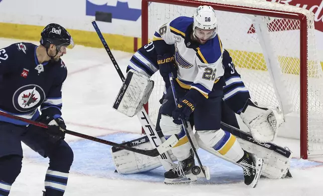 St. Louis Blues' Nathan Walker (26) tips the puck past Winnipeg Jets goaltender Connor Hellebuyck (37) for the goal as Nino Niederreiter (62) defends during first period NHL playoff action in Winnipeg on Wednesday, April 30, 2025. (John Woods/The Canadian Press via AP)