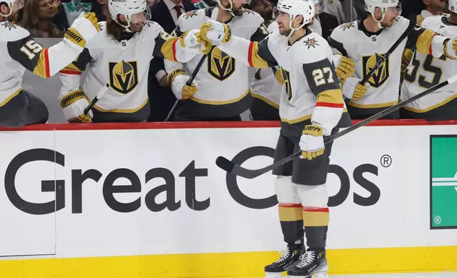 Vegas Golden Knights defenseman Shea Theodore (27) is congratulated by teammates after scoring a power play goal during the first period of Game 6 of a first-round NHL hockey playoff series against the Minnesota Wild, Thursday, May 1, 2025, in St. Paul, Minn. (AP Photo/Bailey Hillesheim)