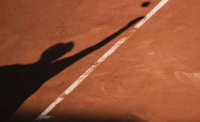 Italy's Matteo Gigante casts his shadow on the court as he serves against Ben Shelton of the U.S.during their third round match of the French Tennis Open, at the Roland-Garros stadium, in Paris, Friday, May 30, 2025. (AP Photo/Thibault Camus)