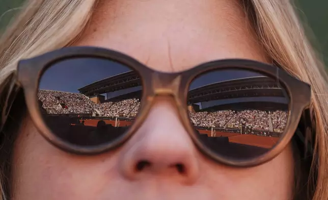 The Suzanne-Lenglen court is reflected in the glasses of a spectators as Italy's Lorenzo Musetti plays Argentina's Mariano Navone during their third round match of the French Tennis Open, at the Roland-Garros stadium, in Paris, Friday, May 30, 2025. (AP Photo/Lindsey Wasson)