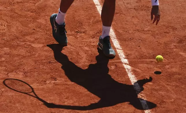 Italy's Lorenzo Musetti casts his shadow on the court as he bounces the ball before serving to Argentina's Mariano Navone during their third round match of the French Tennis Open, at the Roland-Garros stadium, in Paris, Friday, May 30, 2025. (AP Photo/Lindsey Wasson)