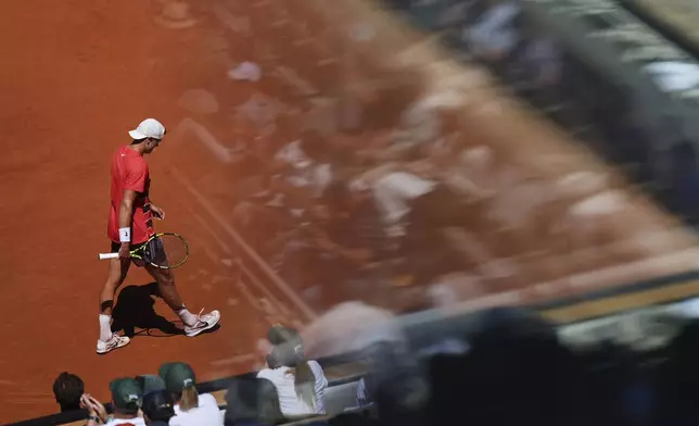 Denmark's Holger Rune is reflected in a glass as he walks on the court while playing France's Quentin Halys during their third round match of the French Tennis Open, at the Roland-Garros stadium, in Paris, Friday, May 30, 2025. (AP Photo/Lindsey Wasson)