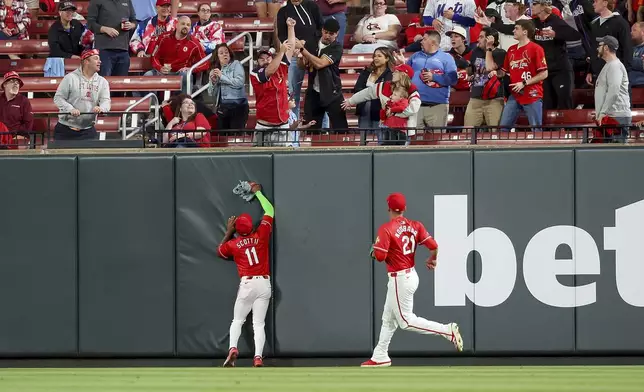 St. Louis Cardinals' Victor Scott II (11) and Lars Nootbaar (21) watch as fans vie for a home run ball hit by New York Mets' Brandon Nimmo during the seventh inning of a baseball game Friday, May 2, 2025, in St. Louis. (AP Photo/Scott Kane)