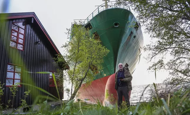 Johan Helberg stands next to his house, with the container ship NCL Salten in the background, after the 135-meter-long ship ran aground in the Trondheimsfjord, outside Byneset, in Trondheim, Norway, Thursday May 22, 2025. (Jan Langhaug/NTB Scanpix via AP)