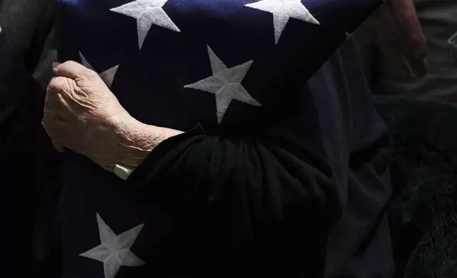 Virginia "Ginny" Pineiro holds a folded American flag during the interment for Staff Sgt. Eugene Darrigan at the cemetery behind St. Mary's church, Saturday, May 24, 2025, in Wappingers Falls, N.Y. Darrigan was buried in his hometown after his remains were recovered from a World War II bomber that crashed into the water off the coast of Papaua New Guinea on March 11, 1944. (AP Photo/Heather Khalifa)