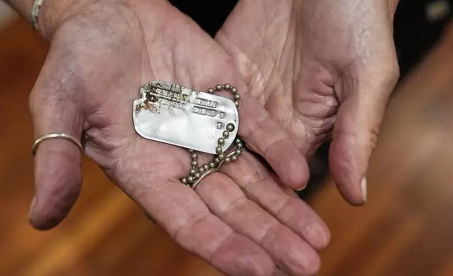 Diane Christie holds a recovered dog tag belonging to her uncle, World War II U.S. Army Air Forces 2nd Lt. Thomas Kelly, Friday, May 23, 2025, in San Leandro, Calif., whose remains had been missing since being killed when the World War II B-24 bomber, Heaven Can Wait, was hit by anti-aircraft fire and crashed into the waters off the coast of Papua New Guinea on March 11, 1944. (AP Photo/Godofredo A. Vásquez)