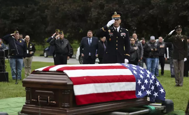 Jason Fetterolf of the U.S. Army Reserve salutes during the interment for World War II U.S. Army Air Forces Staff Sgt. Eugene Darrigan at the cemetery behind St. Mary's church, Saturday, May 24, 2025, in Wappingers Falls, N.Y. Darrigan was buried in his hometown after his remains were recovered from the World War II bomber that crashed into the water off the coast of New Guinea on March 11, 1944. (AP Photo/Heather Khalifa)