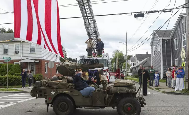 People line the street as the procession carrying the remains of World War II U.S. Army Air Forces Staff Sgt. Eugene Darrigan passes through to St. Mary's church, Saturday, May 24, 2025, in Wappingers Falls, N.Y. Darrigan was buried in his hometown after his remains were recovered from a World War II bomber that crashed into the water off the coast of Papua New Guinea on March 11, 1944. (AP Photo/Heather Khalifa)