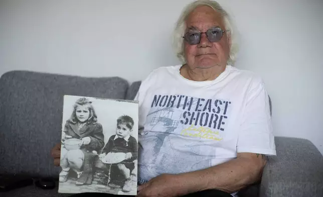Ben Buitenhuis, a 83-year-old surivor of the 1944-1945 Hunger Winter, poses with a picture of himself as a young boy during the Hunger Winter in Delft, Netherlands, Tuesday, April 29, 2025. (AP Photo/Peter Dejong)