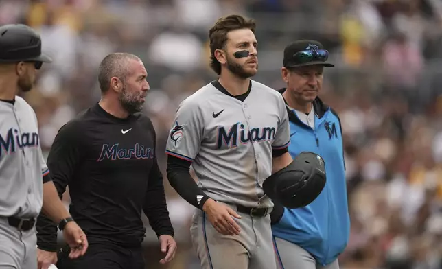 Miami Marlins' Connor Norby, second from right, walks to first after being hit in the helmet by a pitch during the eighth inning of a baseball game against the San Diego Padres Wednesday, May 28, 2025, in San Diego. (AP Photo/Gregory Bull)