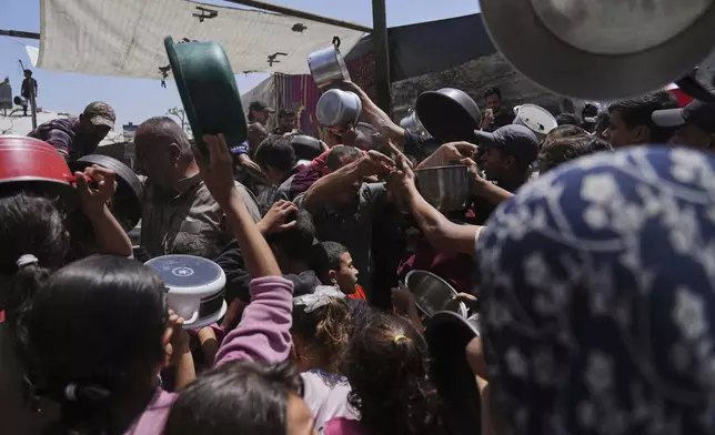 Palestinians struggle to get donated food at a community kitchen in Jabalia, northern Gaza Strip, Monday, May 19, 2025. (AP Photo/Jehad Alshrafi)