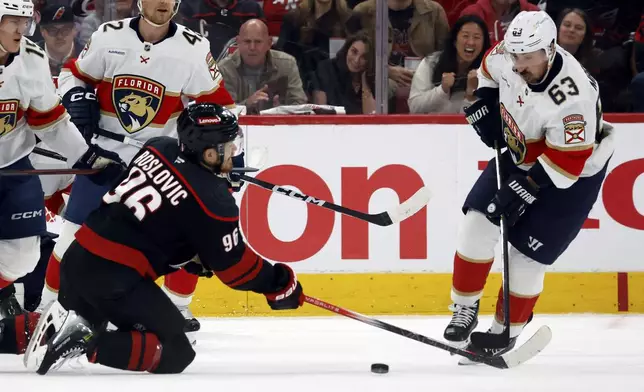 Florida Panthers' Brad Marchand (63) takes the loose puck away from Carolina Hurricanes' Jack Roslovic (96) during the first period of Game 2 of the NHL hockey Stanley Cup Eastern Conference finals in Raleigh, N.C., Thursday, May 22, 2025. (AP Photo/Karl DeBlaker)