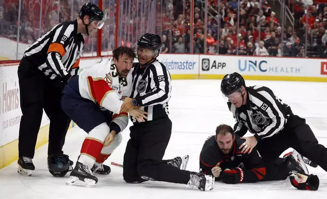 Florida Panthers' Brad Marchand, left, is separated by officials from Carolina Hurricanes' Shayne Gostisbehere (4) during the third period of Game 1 of the NHL hockey Stanley Cup Eastern Conference finals in Raleigh, N.C., Tuesday, May 20, 2025. (AP Photo/Karl DeBlaker)