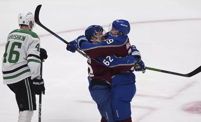 Colorado Avalanche center Nathan MacKinnon, right, celebrates after being awarded a goal with left wing Artturi Lehkonen, center, as Dallas Stars defenseman Ilya Lyubushkin reacts in the third period of Game 6 of an NHL first-round hockey playoff series Thursday, May 1, 2025, in Denver. (AP Photo/David Zalubowski)