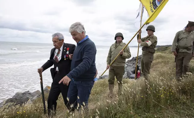 FILE - World War II D-Day veteran and Penobscot Elder from Maine, Charles Norman Shay, left, walks in the dunes overlooking Omaha Beach with men in WWII period uniforms after a Native American ceremony at his memorial in Saint-Laurent-sur-Mer, Normandy, France, June 5, 2020. (AP Photo/Virginia Mayo, File)