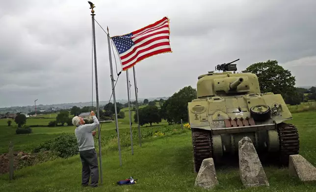 FILE - Director of the Remember Museum 1939-1945, Marcel Schmetz raises an U.S. flag next to a WWII American Sherman tank in Thimister-Clermont, Belgium, July 1, 2020. (AP Photo/Francisco Seco, File)