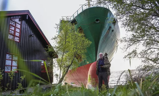 Johan Helberg stands next to his house, with the container ship NCL Salten in the background, after the 135-meter-long ship ran aground in the Trondheimsfjord, outside Byneset, in Trondheim, Norway, Thursday May 22, 2025. (Jan Langhaug/NTB Scanpix via AP)