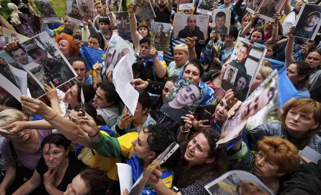People show photos of their missed relatives to Ukrainian soldiers during a POWs exchange between Russia and Ukraine, in Chernyhiv region, Ukraine, Saturday, May 24, 2025. (AP Photo/Evgeniy Maloletka)