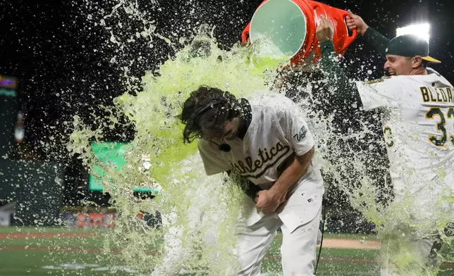 Athletics' Jacob Wilson gets dunked as after the team's walk-off win against the Seattle Mariners after the 11th inning of a baseball game Monday, May 5, 2025, in West Sacramento, Calif. (AP Photo/Scott Marshall)