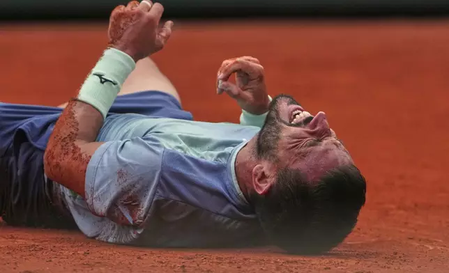 Bosnia and Herzegovina's Damir Dzumhur grimaces in pain after falling while playing France's Giovanni Mpetshi Perricard during their second round match of the French Tennis Open, at the Roland-Garros stadium, in Paris, Wednesday, May 28, 2025. (AP Photo/Lindsey Wasson)