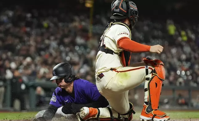 Colorado Rockies' Jordan Beck, left, scores next to San Francisco Giants catcher Patrick Bailey on Hunter Goodman's single during the eighth inning of a baseball game Thursday, May 1, 2025, in San Francisco. (AP Photo/Godofredo A. Vásquez)