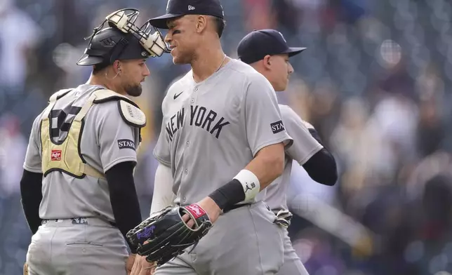 New York Yankees right fielder Aaron Judge, front, congratulates catcher J.C. Escarra, back left, and relief pitcher Luke Weaver after a baseball game against the Colorado Rockies, Sunday, May 25, 2025, in Denver. (AP Photo/David Zalubowski)