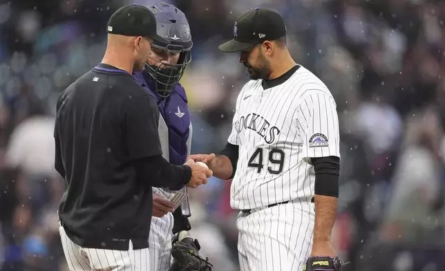 Colorado Rockies interim manager Warren Schaeffer, left, takes the ball from starting pitcher Antonio Senzatela (49) who is pulled from the mound while catcher Hunter Goodman, center, looks on in the top of the fifth inning of a baseball game against the New York Yankees, Sunday, May 25, 2025, in Denver. (AP Photo/David Zalubowski)