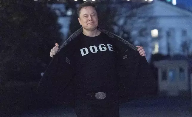 FILE - Elon Musk flashes his t-shirt that reads "DOGE" to the media as he walks on South Lawn of the White House, in Washington, March 9, 2025. (AP Photo/Jose Luis Magana, File)