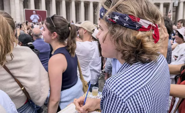 Notre Dame's architecture college student Wesley Buonerba, wearing a us flag bandanna, does a watercolor sketch of the loggia of St. Peter's Basilica during Pope Leo XIV first Sunday blessing of faithful gathered in the square for the traditional blessing, Sunday, May 11, 2025. (AP Photo/Giovanna Dell'Orto)