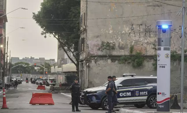 Police officers stand guard in a downtown area popularly known as "Crackland" in Sao Paulo, Monday, May 19, 2025. (AP Photo/Andre Penner)