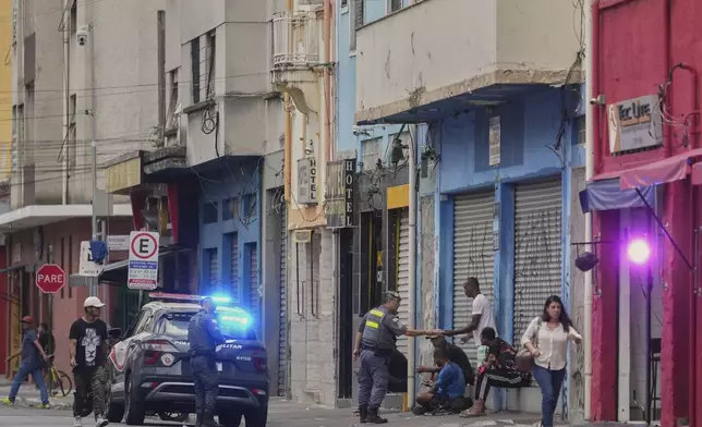 Police officers check the documents of people in a downtown area popularly known as "Crackland" in Sao Paulo, Monday, May 19, 2025. (AP Photo/Andre Penner)