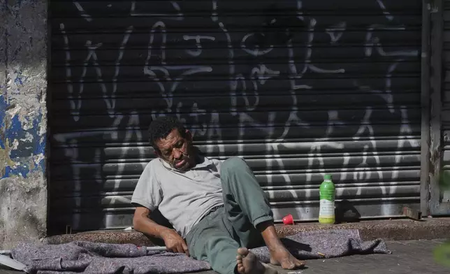A homeless man sleeps on the sidewalk in a downtown area popularly known as "Crackland" in Sao Paulo, Tuesday, May 20, 2025. (AP Photo/Andre Penner)