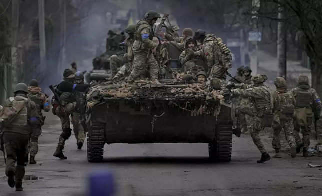 FILE - Ukrainian servicemen climb on a vehicle outside Kyiv, Ukraine, on April 2, 2022. (AP Photo/Vadim Ghirda, File)