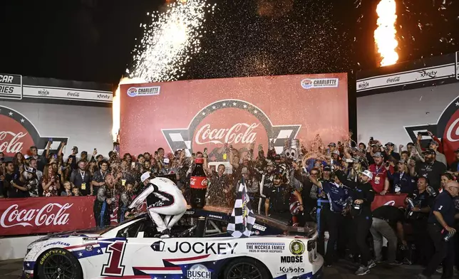 Ross Chastain, front, climbs out of his car in Victory Lane after winning a NASCAR Cup Series auto race at Charlotte Motor Speedway, Sunday, May 25, 2025, in Concord, N.C. (AP Photo/Matt Kelley)