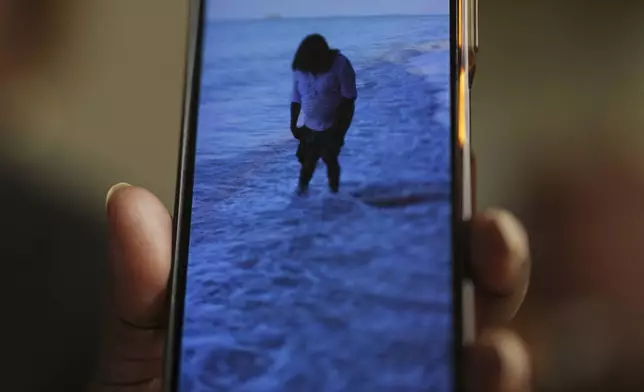 Chagossian Bernadette Dugasse shows photos of the Chagos Islands during an interview with The Associated Press, at her home in London, Tuesday, March 25, 2025. (AP Photo/Kin Cheung)