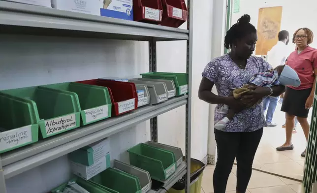 A patient cradles a baby while waiting to receive medicine at New Hope Hospital in Plaine-du-Nord, Haiti, Wednesday, May 21, 2025. (AP Photo/Patrice Noel)