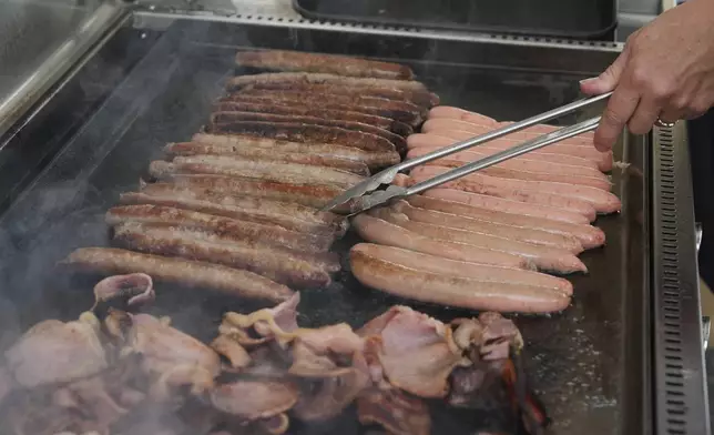 A volunteer cooks sausages on a BBQ outside a polling booth at Sydney's Bondi Beach, Saturday, May 3, 2025. (AP Photo/Mark Baker)