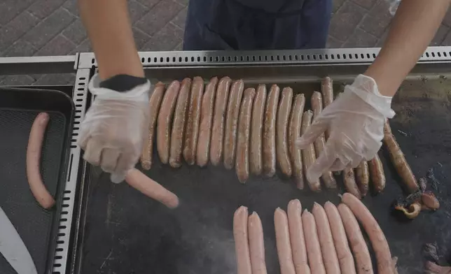 A volunteer cooks sausages on a BBQ outside a polling booth at Sydney's Bondi Beach, Saturday, May 3, 2025. (AP Photo/Mark Baker)