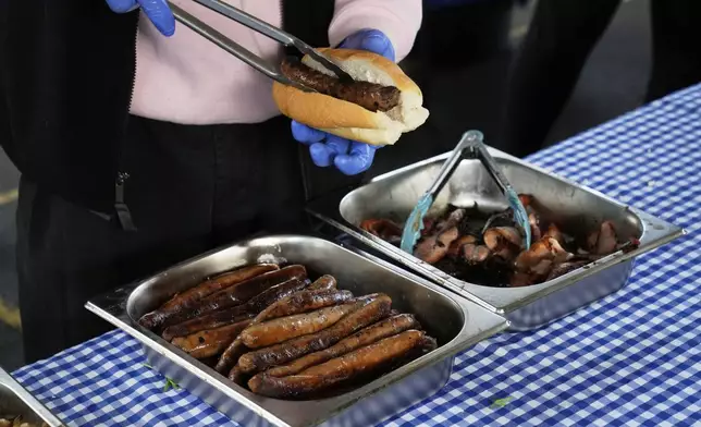 A worker prepares a "Democracy Sausage" at the Marrickville Public School in Sydney, Australia, Saturday, May 3, 2025, for someone who has voting in the general election. (AP Photo/Rick Rycroft)