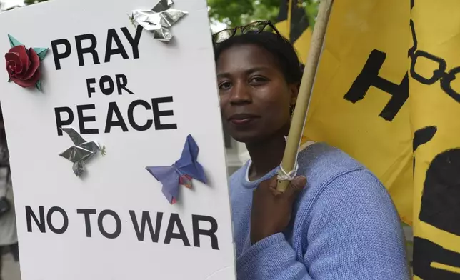 Casey Oware, a member of the Princeton Friends Meeting, holds a banner after meeting members of the Quaker March to Washington in Princeton, N.J., on Wednesday May 7, 2025. (AP Photo/Luis Andres Henao)