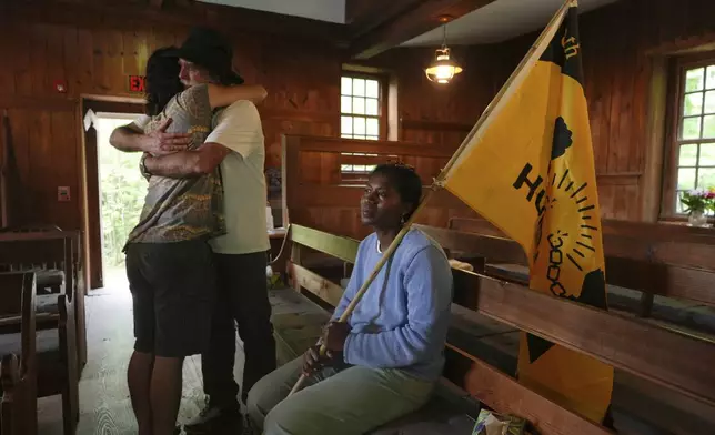 Casey Oware, a member of the Princeton Friends Meeting, seated, holds a flag while Stuart Sydenstricker, right, and Jules Wing Vasquez hug after completing a portion of the Quaker March to Washington at the Quaker Meeting House in Princeton, N.J. (AP Photo/Luis Andres Henao)