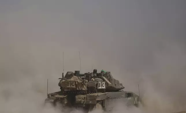 FILE - Israeli soldiers move tanks around a staging area near the border with the Gaza Strip in southern Israel, Sunday, May 18, 2025. (AP Photo/Ariel Schalit, File)