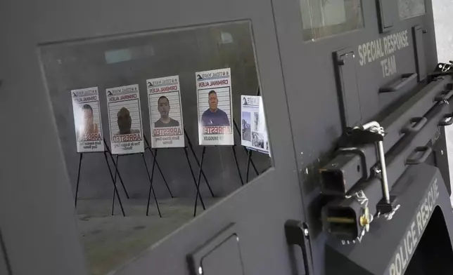 Posters of alleged criminals who officials said were arrested in a recent immigration enforcement operation are reflected in a Department of Homeland Security vehicle during a press conference with Gov. Ron DeSantis at the South Florida office of U.S. Immigration and Customs Enforcement and Enforcement and Removal Operations, Thursday, May 1, 2025, in Miramar, Fla. (AP Photo/Rebecca Blackwell)